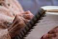 wrinkled hands for elderly person writing notes on here note book in living room Royalty Free Stock Photo