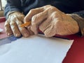 wrinkled hands holding a pen to write on blank paper Royalty Free Stock Photo