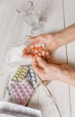 Senior hands with pills and drugs on table, glass of water.