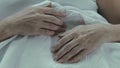 Wrinkled hands of senior woman lying on stomach, incurable disease, unhealthy