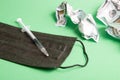 wrinkled stallar bills black medical face mask and insulin syringe with medicine on a green background, copy space, coronavirus ep