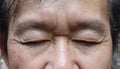 Wrinkles around closed eyes of Asian elder man