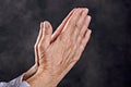 Wrinkly hands of elderly woman praying