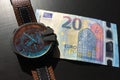 Wrist watch with leather strap near the banknote on a dark background, watch on top of money, time is money, wristwatch, European Royalty Free Stock Photo