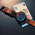 Watch with leather strap near the banknote on a dark background, watch on top of money, time is money, wristwatch, European curren Royalty Free Stock Photo