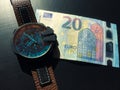 Watch with leather strap near the banknote on a dark background, watch on top of money, time is money, wristwatch, European curren Royalty Free Stock Photo