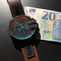 Watch with leather strap near the banknote on a dark background, watch on top of money, time is money, wristwatch, European curren Royalty Free Stock Photo