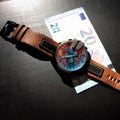 Wrist watch with leather strap near the banknote on a dark background Royalty Free Stock Photo