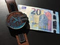 Wrist watch with leather strap near the banknote on a dark background Royalty Free Stock Photo