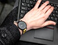 Wristwatch. Hand on the keypad of notebook