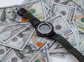 Wristwatch lies on background of scattered American dollars