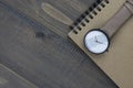 Wristwatch and notebook on wooden table