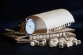 A wristwatch, a notebook and the word linguistics, made up of wooden cubes, on a dark background. Concept for research in