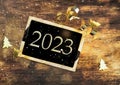 2023 writen on a black little board on illuminated wooden background