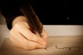 Writer holds a fountain pen over writing paper and a signature