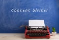 writer's workplace - red typewriter on blue blackboard background with text "content writer Royalty Free Stock Photo