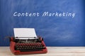 writer's workplace - red typewriter on blue blackboard background with text "content marketing Royalty Free Stock Photo