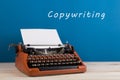 writer's workplace - typewriter on blue blackboard background with text "Copywriting