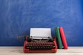 writer's workplace - red typewriter and books on blue blackboard background Royalty Free Stock Photo