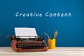 writer's workplace - red typewriter and stationery on blue blackboard background with text "Creative content Royalty Free Stock Photo