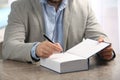 Writer signing autograph in book at table