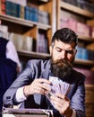 Writer with strict face with typewriter in library with books Royalty Free Stock Photo