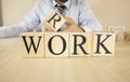 It writes the word work on wooden blocks. The man in the suit puts the block on top. Royalty Free Stock Photo