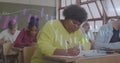 Writing African American student in yellow top taking notes in classroom, with projected bar charts Royalty Free Stock Photo