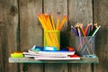 Writing-books and school tools on a wooden shelf.