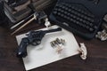 Writing a crime fiction story - old retro vintage typewriter and revolver gun with ammunitions, books, blank paper, old ink pen Royalty Free Stock Photo