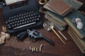 Writing a crime fiction story - old retro vintage typewriter and revolver gun with ammunitions, books, papers, old ink pen Royalty Free Stock Photo