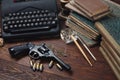 Writing a crime fiction story - old retro vintage typewriter and revolver gun with ammunitions, books, papers, old ink pen Royalty Free Stock Photo
