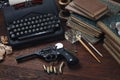 Writing a crime fiction story - old retro vintage typewriter and revolver gun with ammunitions, books, papers, old ink pen Royalty Free Stock Photo