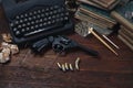 Writing a crime fiction story - old retro vintage typewriter and revolver gun with ammunitions, books, papers, old ink pen Royalty Free Stock Photo