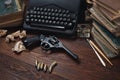 Writing a crime fiction story - old retro vintage typewriter and revolver gun with ammunitions, books, papers, old ink pen Royalty Free Stock Photo