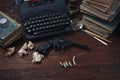 Writing a crime fiction story - old retro vintage typewriter and revolver gun with ammunitions, books, papers, old ink pen
