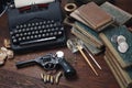 Writing a detective story - old retro vintage typewriter and revolver gun with ammunitions, books, papers, old ink pen