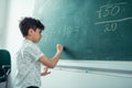 Little concentrated schoolboy writing on the blackboard. Royalty Free Stock Photo