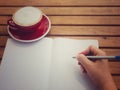 Hand writing on white paper with hot coffee in red cup on wooden table have space for texture