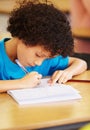 Writing in his homework book. A cute little boy working on his homework in class. Royalty Free Stock Photo