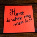 Writing Home is where my mom is on memo post reminder. Text on sticky paper. Mother`s day concept