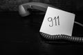 Writing 911 on memo post reminder.  sticky paper surrounded by wire of landline phone Royalty Free Stock Photo