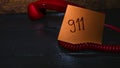 Writing 911 on memo post reminder.  sticky paper surrounded by wire of landline phone Royalty Free Stock Photo