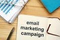 Writing note showing email marketing campaign. The text is written in the notebook. Graphs on the paper sheet, pen, wooden Royalty Free Stock Photo