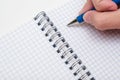 Writing notes or planning a schedule on blank spiral notebook, hand using a pen on a checkered blank paper, copy space Royalty Free Stock Photo
