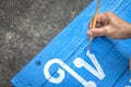 Writing signs board with a brush of watercolors on cement floor background. Painting on wooden board in thai language for advertis