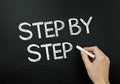 writing STEP BY STEP chalkboard with hand playful creative font progress Royalty Free Stock Photo