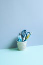 Writing supplies in pen holder on blue desk. blue wall background. stationery, office supply, workspace