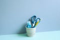 Writing supplies in pen holder on blue desk. blue wall background. stationery, office supply, workspace