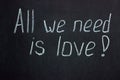 Writing in white chalk on a dark blackboard all we need is love